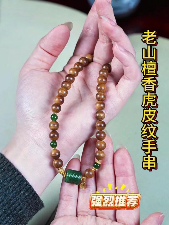 手链赛道文案素材 - 天然老山檀香搭配碧玉桶珠 国风吉祥文玩项链 禅意复古挂饰 天然老山檀香与和田碧玉桶珠的雅致邂逅，造就这条国风禅意颈饰。檀木甄选老料，自带醇厚绵长的淡雅香气，质地温润细腻，经手工打磨尽显木质纹理；碧玉桶珠色泽莹润，玉质通透，无论是日常通勤还是文玩雅聚，都能为穿搭添一份古韵雅致，自用送礼皆是彰显品味的心意之选。#手链 #手串 #文玩 #老山檀香 #木质 - 妮子说串作品